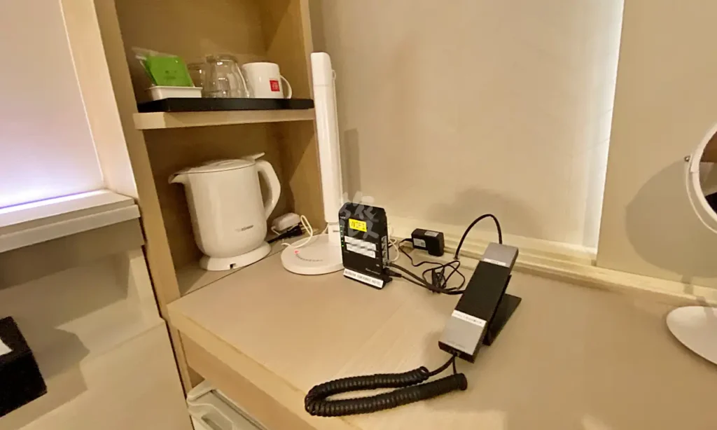 The desk and amenities provided at the Shibuya Tokyu REI Hotel (phone, Wi-Fi, desk lamp, electric kettle, cups, and glasses)